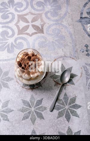 Dessert tiramisu italien classique servi dans des verres. Couches d'éponge imbibée de café et de mascarpone crémeux, saupoudrées de poudre de cacao. Placé sur le motif Banque D'Images