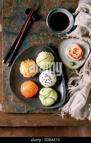 Temari sushi. Boules de sushi tendance avec saumon, avocat, concombre et omelette japonaise sur plaque de céramique brune. Sauce soja, gingembre mariné, baguettes, Li Banque D'Images