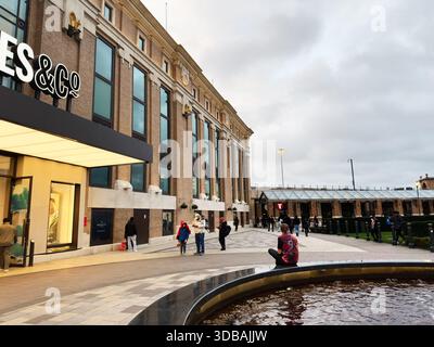 Manchester, Royaume-Uni - 15 novembre 2025 : les gens explorent un élégant quartier commerçant Selfridges and Co à Manchester, avec une architecture en briques, des devantures de magasins, et Banque D'Images