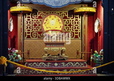 Salle du trône impérial, Vietnam - trône de dragon doré orné, rideaux rouges, parapluies cérémoniels et motifs traditionnels. Banque D'Images