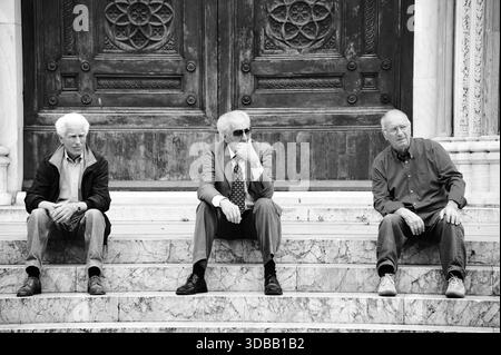Trois habitants sont assis sur les marches du Cattedrale di San Lorenzo, Piazza del Duomo, Grosseto, Italie. 30 avril 2013 Banque D'Images