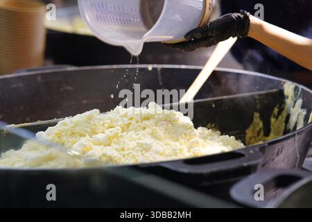 Vue rapprochée des aliments cuits dans une grande casserole que l'eau est versée sur le mélange à un étal de marché.Nantes, France Banque D'Images