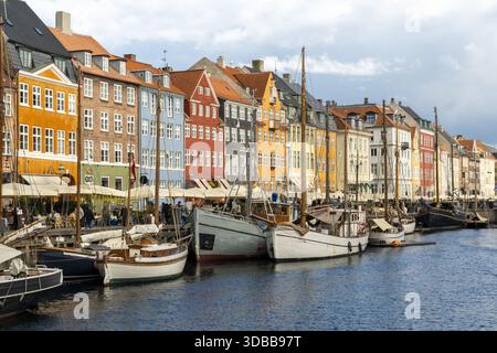 Vue des bâtiments colorés bordant le canal Nyhavn, où les bateaux flottent doucement dans l'eau, reflétant l'atmosphère charmante de la ville, Copenhague, D. Banque D'Images