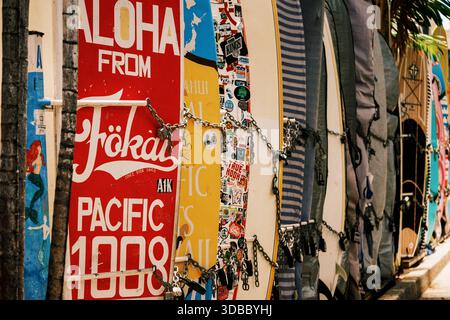 Planches de surf alignées sur un mur avec des motifs colorés et des autocollants dans une zone côtière Banque D'Images