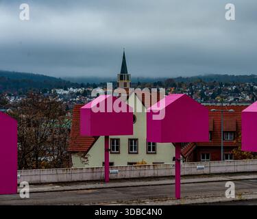 Pink House sculptures Line Roof Promenade surplombant Small Town Church Steeple sous Moody Cloudy Sky Metal Poles et Leafless Trees Frame Muted Arch Banque D'Images