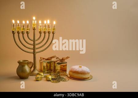 Configuration de célébration Hanukkah. Une menorah, des dreidels, des coffrets cadeaux et des beignets sur fond beige Banque D'Images