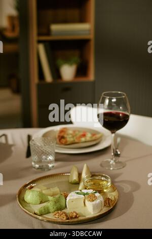 Plateau de fromage avec noix et poires accompagnant un verre de vin rouge Banque D'Images