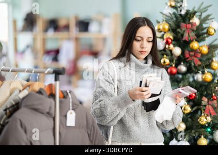 Femme shopper choisit chaud c dans le magasin de vêtements avant Noël Banque D'Images