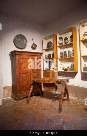 Armoire vintage et banc de travail du bois se tiennent parmi les lanternes historiques et les ustensiles montrant le patrimoine italien et la tradition artisanale magnifiquement préservés Banque D'Images