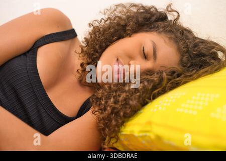 Jeune femme dormant paisiblement sur un oreiller jaune Banque D'Images