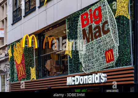 Louvain, Belgique - 14 décembre 2025 : façade du restaurant McDonald's décorée de lumières festives et d'un grand présentoir Big Mac, avec l'emblématique McDonald's Banque D'Images