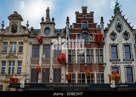 Louvain, Belgique - 14 décembre 2025 : décorations festives de cadeaux de Noël accrochées sur des maisons de guilde historiques dans le centre-ville, mettant en valeur la tradition flamande Banque D'Images
