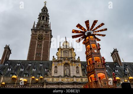 Louvain, Belgique - 14 décembre 2025 : pyramide de Noël en bois vendant des crêpes et des churros au marché d'hiver, situé en face de la KU Louvain University Lib Banque D'Images