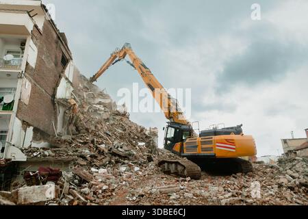 Une excavatrice démolit un appartement dans la ville de Diyarbakir en Turquie. Une excavatrice sur les ruines d'une maison. Banque D'Images