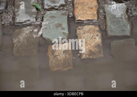 Dublin, Irlande - 10 décembre 2025 - eau trouble au-dessus de divers pavés colorés dans une rue de la ville de Dublin représentant des scènes de rue dans la capitale irlandaise Banque D'Images