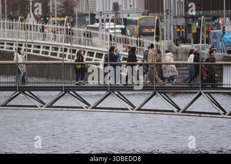 Dublin, Irlande - 10 décembre 2025 - vue lointaine du Millennium Bridge au-dessus de la Liffey avec des piétons passant devant dans la ville de Dublin représentant des scènes de rue dans la capitale irlandaise Banque D'Images