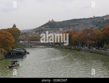 Tbilissi, Géorgie-13 novembre 2025 : Mtkvari aka rivière Kura avec des bateaux et la vieille ville de Tbilissi du Pont de la paix Banque D'Images