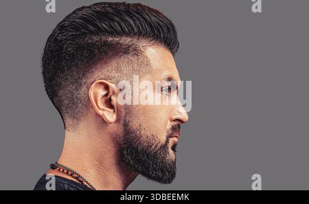 Vue latérale homme barbu isolé sur fond gris. Barbe parfaite. Gros plan de jeune homme barbu, coiffure élégante, barbe Banque D'Images