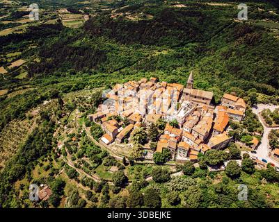 Vue aérienne des toits en terre cuite nichés au milieu de collines verdoyantes, une ville médiévale se prélassant dans la lumière du soleil doré, Groznjan, comté d'Istrie, Croatie. Banque D'Images