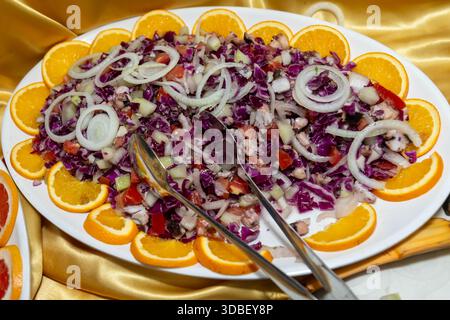 Salade hachée colorée avec chou rouge, tomates, oignons et tranches d'orange sur un plateau Banque D'Images