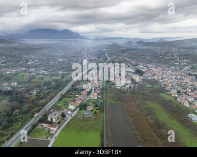 Vue aérienne d'une route traversant une ville entourée de verdure luxuriante, sous un ciel nuageux, Serino, Irpinia, Italie. Banque D'Images