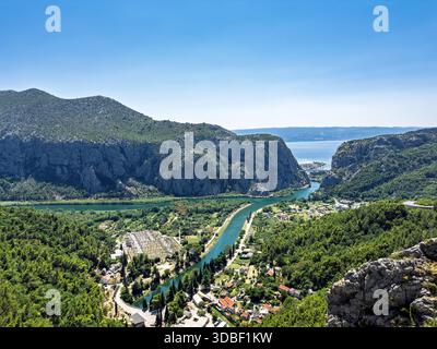 Vue panoramique sur une vallée fluviale avec une centrale hydroélectrique et une infrastructure urbaine, située entre des montagnes calcaires abruptes près de la côte Banque D'Images