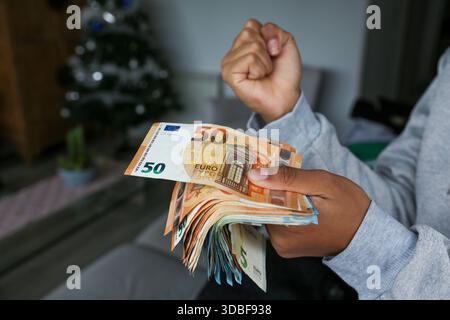 Un tas de billets en euros tenus par les mains d'une femme afro-américaine à la peau claire célébrant qu'elle a cet argent Banque D'Images