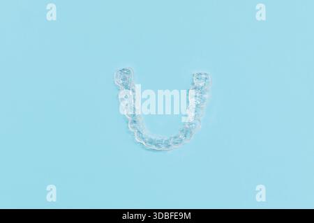 Vue de dessus de dents dentaires transparentes personnalisées protège-morsures aligners clairs pour la mâchoire inférieure sur fond bleu Banque D'Images