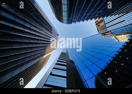 Vue spectaculaire en bas angle des gratte-ciels modernes en verre dominant le ciel bleu clair dans le quartier financier urbain Banque D'Images