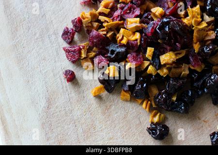 Gros plan de fruits séchés hachés sur une planche à découper en bois. Ingrédients pour granola maison, cuisson au four et collations saines Banque D'Images