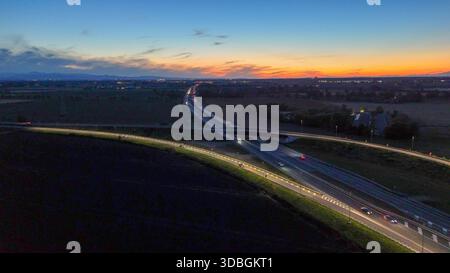 Circulation routière se déplaçant le long de l'autoroute A21 près de Piacenza Brescia la nuit, les véhicules créant des sentiers légers sur les infrastructures et le réseau routier pendant l'dus Banque D'Images