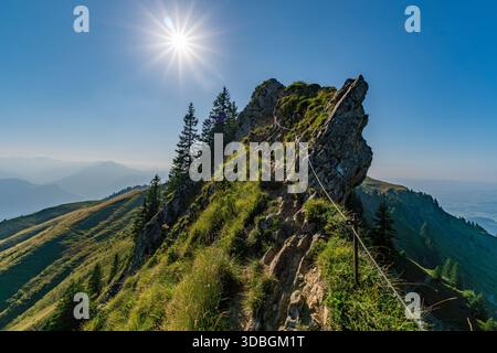 Une vue panoramique à couper le souffle sur les sentiers de montagne accidentés serpentant à travers une végétation luxuriante sous un ciel ensoleillé rayonnant, évoquant la sérénité et l'aventure Banque D'Images