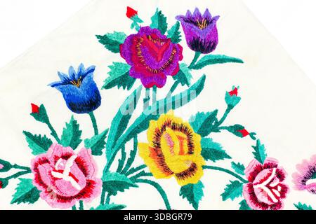 Tissu avec broderie florale brillante représentant différents types de fleurs et de feuilles. Le design présente des tulipes et des roses de différentes couleurs. Banque D'Images