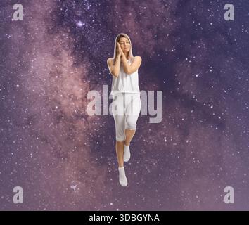 Jeune femme en pyjama dormant et lévitant dans les étoiles Banque D'Images