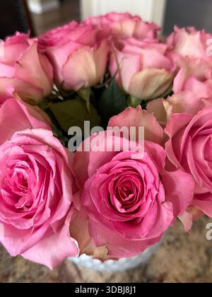 Des arrangements luxuriants de roses roses roses vibrantes dans un vase en verre, associés à des roses pêche pour un affichage floral complet, romantique et élégant. Banque D'Images