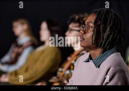 Jeune adulte Noir participant à la présentation avec un public diversifié Banque D'Images