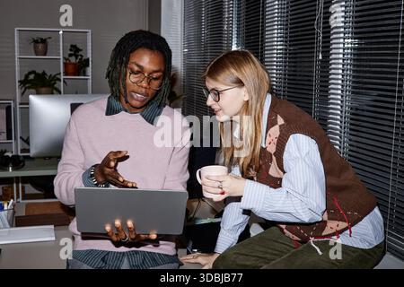 Jeune homme noir adulte expliquant le projet à une jeune femme caucasienne adulte Banque D'Images