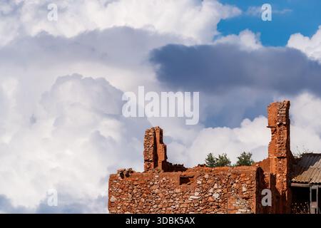 Gros plan sur les ruines de briques et de pierres rouges en ruines d'un ancien bâtiment, contrastées de façon spectaculaire par une vaste toile de fond de blanc immense et bouillonnant Banque D'Images