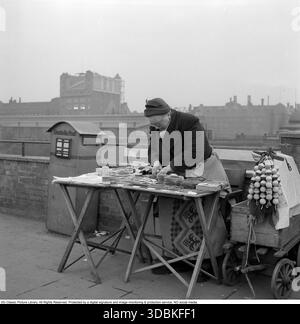Berlin est 1957. Une femme âgée est vue vendre des cartes postales à un stand dans la rue. Roland Palm ref 10/78 :01 Banque D'Images