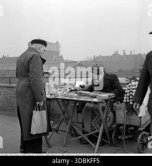 Berlin est 1957. Une femme âgée est vue vendre des cartes postales à un stand dans la rue. Roland Palm ref 10/78 :02 Banque D'Images