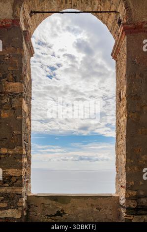 Paysage ensoleillé de la mer méditerranée vu à travers une fenêtre s'ouvrant dans un mur historique vu en Ligurie, Italie Banque D'Images