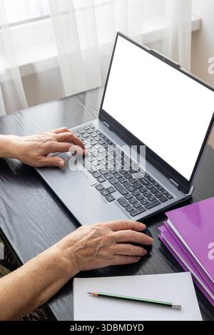 Femme âgée de 70 ans et plus utilisant un ordinateur portable à la maison pour le travail à distance, la communication en ligne et la gestion financière. Concept de vieillissement actif, adoption de la technologie, Banque D'Images