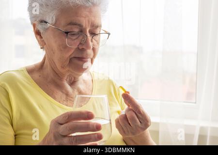 Femme âgée prenant une capsule de santé. Santé à l'âge adulte, maintien de l'activité et de l'énergie. Prévention des maladies, utilisation de vitamines et de suppléments, Trea Banque D'Images