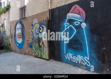 Street art dans une ruelle, avec un graffiti bleu et blanc proéminent sur un mur noir, figurine stylisée de chapeau de Père Noël, Istanbul turquie, beyouglu Banque D'Images
