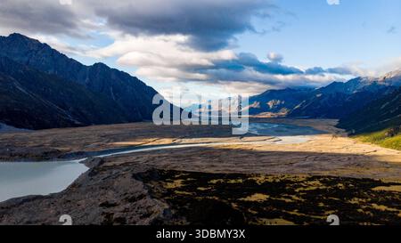Vue aérienne de la rivière tressée du glacier Tasman qui coule à travers le fond de la vallée aride et ensoleillé, contre les sommets imposants du mont Cook, Tasma Banque D'Images
