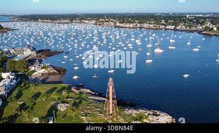 Un phare est vu au loin au-dessus d'un plan d'eau. L'eau est pleine de bateaux, et le ciel est clair et bleu. Marblehead Harbor à Marblehead, Banque D'Images