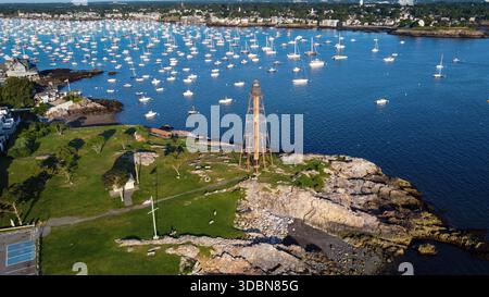 Un phare est vu au loin au-dessus d'un plan d'eau. L'eau est pleine de bateaux, et le ciel est clair et bleu. Marblehead Harbor à Marblehead, Banque D'Images