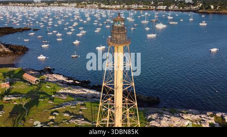 Un phare est vu au loin au-dessus d'un plan d'eau. L'eau est pleine de bateaux, et le ciel est clair et bleu. Marblehead Harbor à Marblehead, Banque D'Images