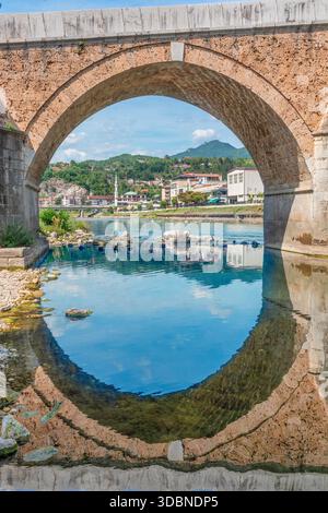 Vue à travers l'arc de pierre de la Stara Cuprija (vieux pont) reflétant dans la rivière Neretva, Konjic, canton d'Herzégovine-Neretva, Bosnie-Herzégovine Banque D'Images