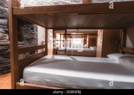 Vue intérieure du dortoir de l'auberge vu à travers des lits superposés en bois, chambre à coucher commune propre avec matelas et oreillers, hébergement de voyage de budget, Banque D'Images